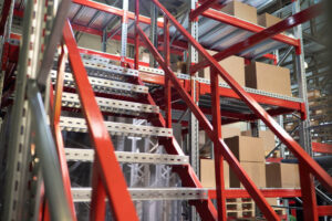 Metal stairs with red banister leading up to storage racking